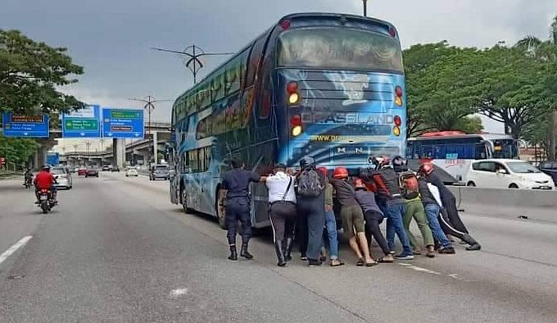 With the help of motorists, the Johor Baru Utara traffic police tried to move the bus at Km12 of Jalan Johor Baharu-Air Hitam but failed as the rear wheels had jammed. — Picture via Facebook/Police Daerah Johor Bahru Utara