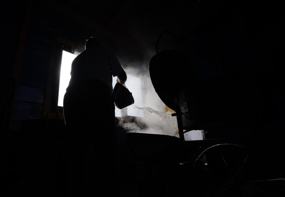 Miroslav Milosevic with friend washes the container after making brandy in the village of Rozanci, 20 kilometers south of Belgrade, Serbia, Friday, Nov. 11, 2022. The U.N.'s culture and education organization is set later this month to review Serbia's bid to include "social practices and knowledge related to the preparation and use of the traditional plum spirit - sljivovica" on the list of world intangible cultural heritage. (AP Photo/Darko Vojinovic)