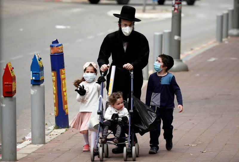 FILE PHOTO: An ultra-Orthodox Jewish family wearing masks walk on a pavement in Bnei Brak, a town badly affected by the coronavirus disease (COVID-19), and which Israel declared a "restricted zone" due to its high rate of infections, near Tel Aviv