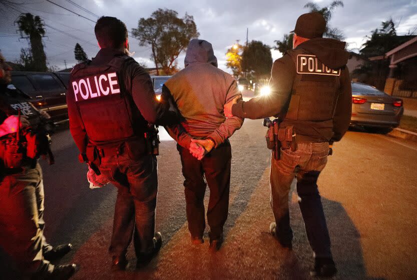 BELL GARDENS, CA - MARCH 16, 2020 U.S. Immigration and Customs Enforcement (ICE) agents joined by (CBP) U.S. Customs & Border Protection agents take Marcos Correa into custody as ICE officers are joined by CBP agents in the last few weeks, as more resources are deployed in sanctuary cities. (Al Seib / Los Angeles Times)