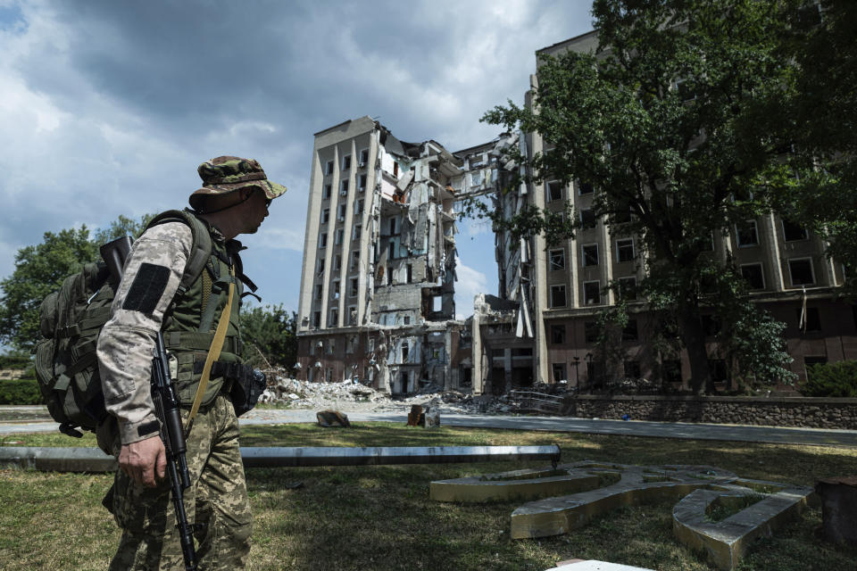 A Ukrainian serviceman stands in front of headquarters of the Mykolaiv Regional Military Administration building destroyed by a Russian attack in Mykolaiv, Ukraine, Friday, Aug. 5, 2022. (AP Photo/Evgeniy Maloletka)