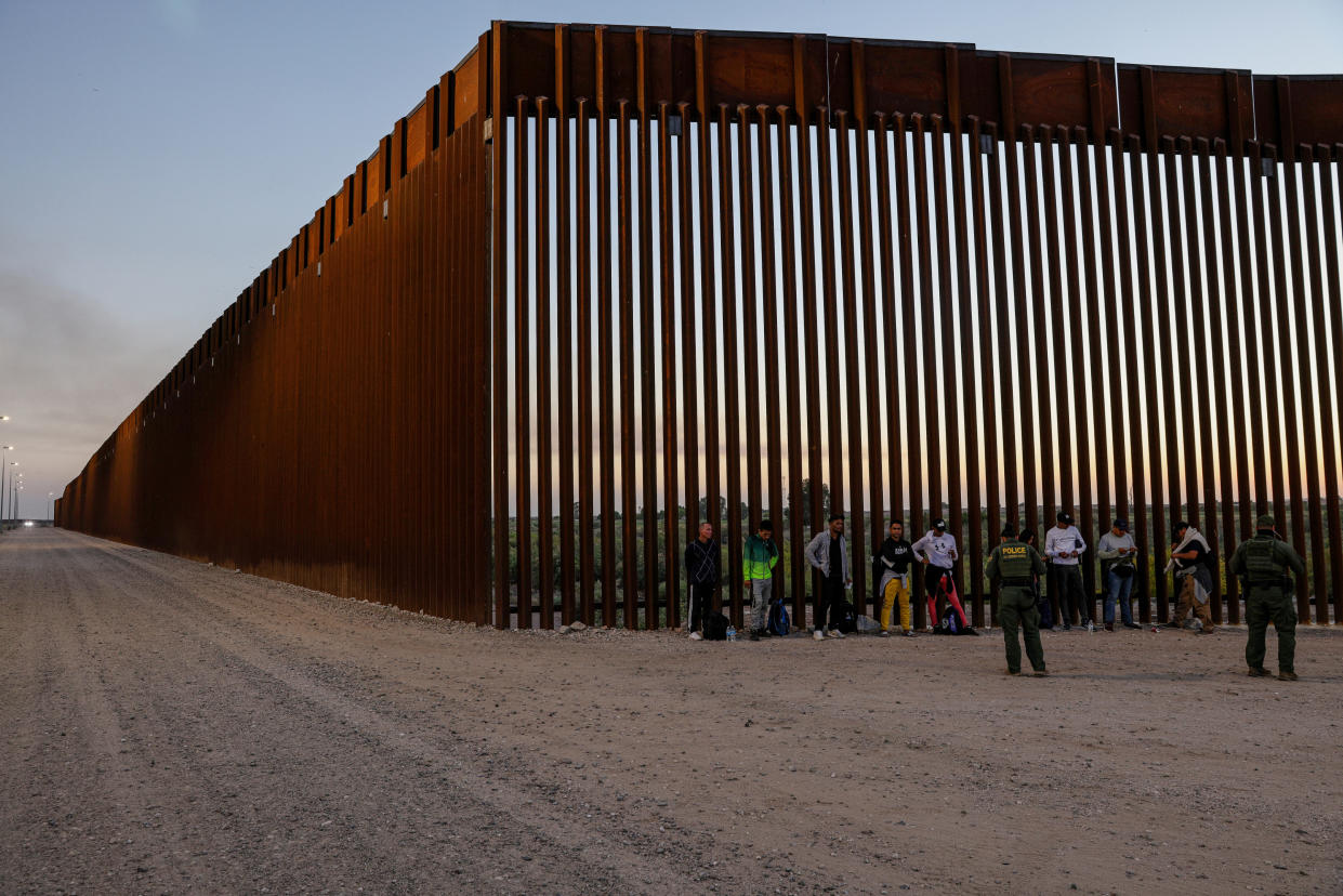 Un grupo de migrantes es detenido para ser procesado tras entregarse en un muro fronterizo estadounidense con México, en Yuma, Arizona, el 11 de mayo de 2023. (Adriana Zehbrauskas/The New York Times)