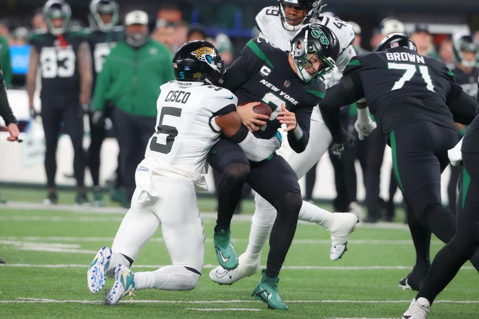 Jacksonville Jaguars safety Andre Cisco (5) sacks New York Jets quarterback Zach Wilson (2) during the first quarter Thursday night.  (Photo by Rich Graessle/Icon Sportswire via Getty Images)