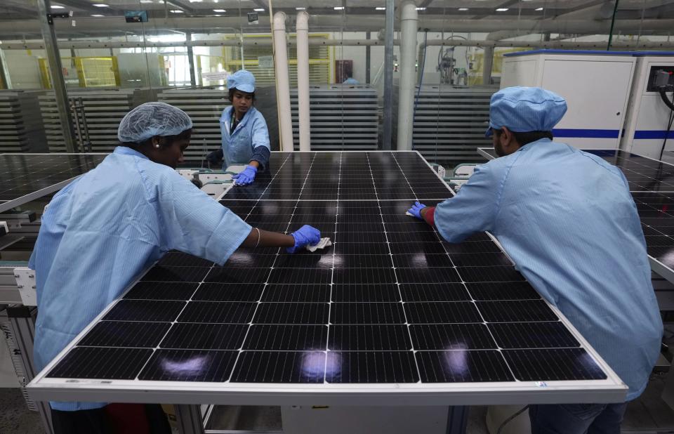 Machine operators clean a solar panel at Premier Energies Solar on the outskirts of Hyderabad, India, Wednesday, Jan. 25, 2023. Solar developers in India fear that a tax meant to encourage Indian manufacture of solar components will slow down the installation of solar power this year. (AP Photo/Mahesh Kumar A.)