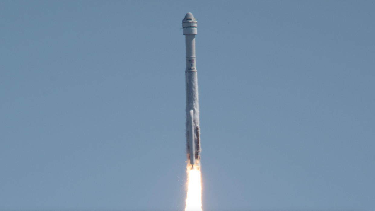  Closeup view of a white rocket climbing into a blue sky. 