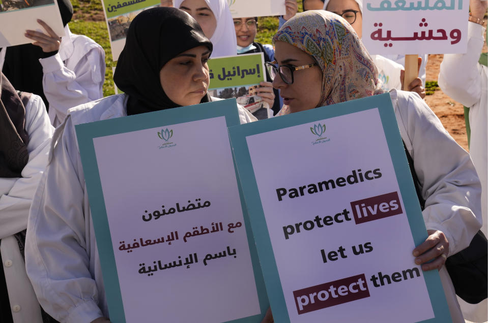 Lebanese paramedics hold placards as they attend a protest supporting their colleagues in Gaza and Lebanon in front of the headquarters of U.N. Economic and Social Commission for Western Asia (ESCWA) in Beirut, Lebanon, Tuesday, March 12, 2024. The Arabic placard on the left reads:"In the name of humanity, we stand in solidarity with the paramedics teams."(AP Photo/Hussein Malla)