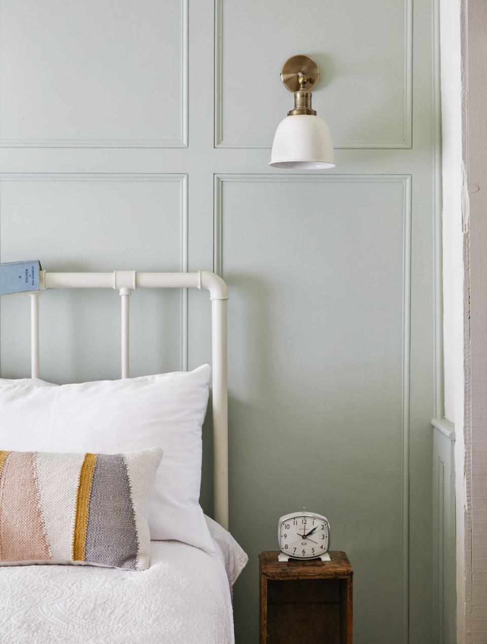 iron bedstead and pastel panelled wall