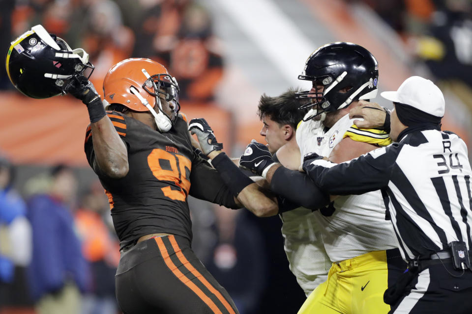 FILE - In this Nov. 14, 2019, file photo, Cleveland Browns defensive end Myles Garrett, left, gets ready to hit Pittsburgh Steelers quarterback Mason Rudolph, second from left, with a helmet during the second half of an NFL football game in Cleveland. The Browns star defensive end can't undo his helmet-swinging attack on Rudolph last season or the six-game NFL suspension that ensued. That damage is done and irreparable. But he isn't going to let the incident define him, and as he prepares for his fourth season, he's not worried about any outside perceptions of him as a person or player.  (AP Photo/Ron Schwane, File)