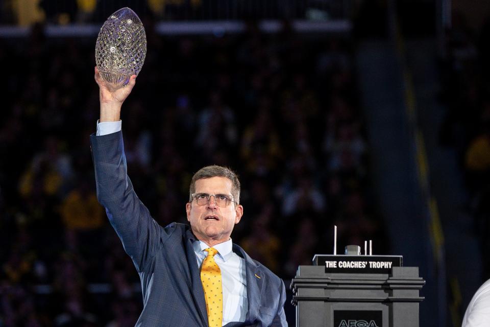 Michigan head coach Jim Harbaugh lifts the AFCA Coaches' Trophy during the national championship celebration at Crisler Center in Ann Arbor on Saturday, Jan. 13, 2024.