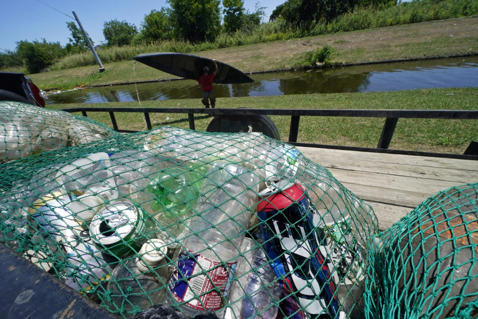 Collected trash sits in bags as Jack Bates, of Osprey Initiative, launches a canoe to clean out one of the company’s Litter Gitters -- traps to collect trash in waterways before it can travel into larger bodies of water, in New Orleans, Friday, May 27, 2022. (AP Photo/Gerald Herbert)