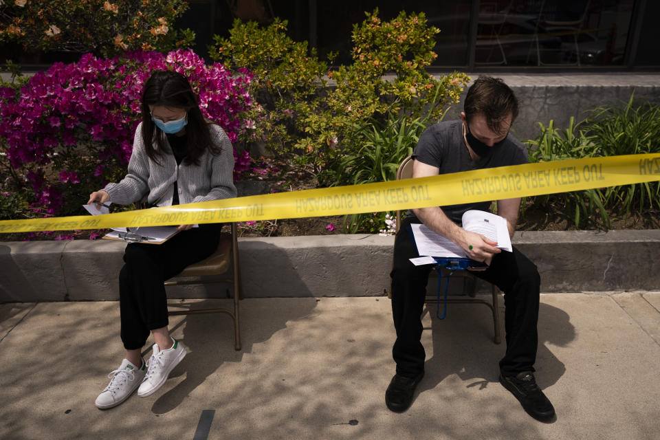 Karl Pajak, 28, right, and Yuting Yu, 22, fill out forms to get the Moderna vaccine at a vaccination center in the Chinatown neighborhood of Los Angeles, Monday, April 12, 2021. The city of Los Angeles has opened up vaccines to younger people, days ahead of the state broadening eligibility to everyone 16 and up. (AP Photo/Jae C. Hong)