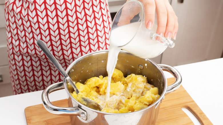 Adding milk to boiled potatoes.