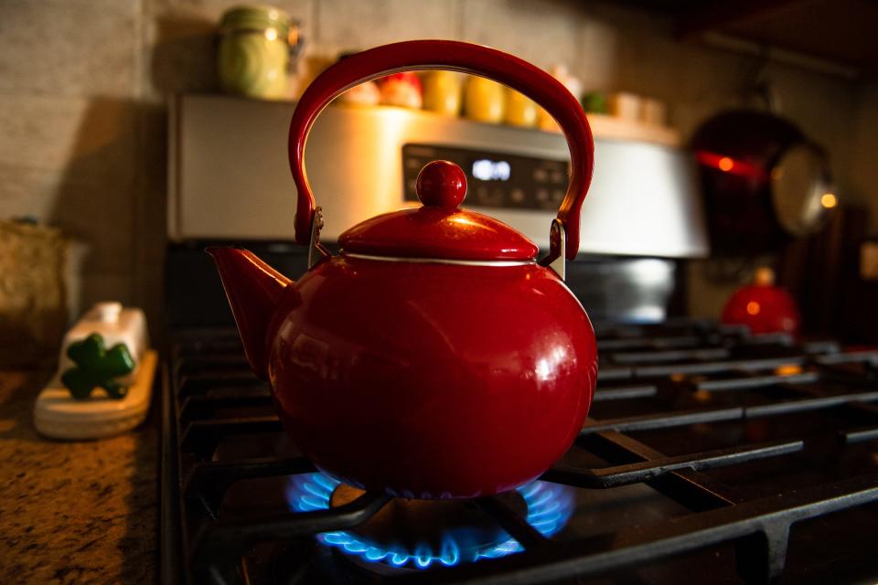 A kettle warms over a burner on a gas cooktop on Feb. 13, 2023.