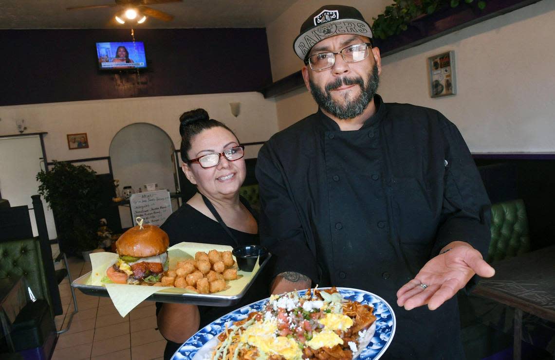 Owner and chef Marcial Gonzalez, right, holding a plate of chilaquiles, stands with his wife Michelle Gonzalez, left, holding their west side burger, have opened Grandma Jane’s Kitchen, a new restaurant on E Street near downtown Fresno’s Chinatown. Photographed Tuesday, Oct. 11, 2022.