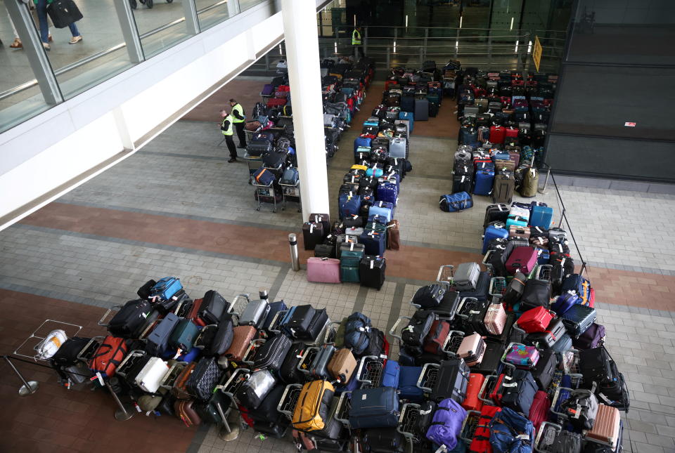 Airport workers stand next to lines of passenger luggage arranged outside Terminal 2 at Heathrow Airport in London, Britain, June 19, 2022. REUTERS/Henry Nicholls