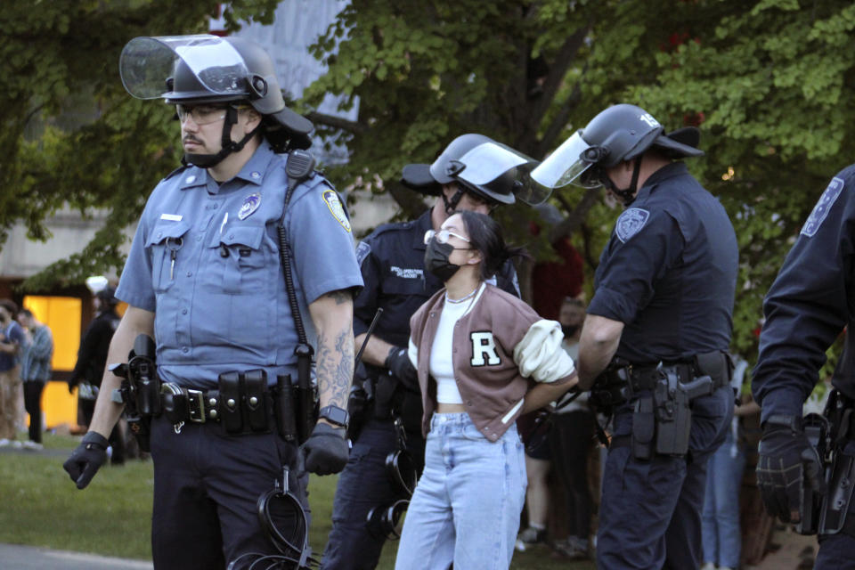 Members of law enforcement place a person in handcuffs, Tuesday, May 7, 2024, on the University of Massachusetts Amherst campus, in Amherst, Mass. Police moved in Tuesday night to break up an encampment at the school in what appeared in video to be an hours-long operation as dozens of police officers in riot gear systematically tore down tents and took protesters into custody. The protesters established the tent encampment to demonstrate against the war in Gaza. (Kalinka Kornacki via AP)