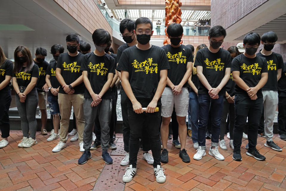 University students observe one minute silence to mourn those killed in the 1989 Tiananmen crackdown, in front of the "Pillar of Shame" statue at the University of Hong Kong, Friday, June 4, 2021. Police arrested an organizer of Hong Kong's annual candlelight vigil remembering the deadly Tiananmen Square crackdown and warned people not to attend the banned event Friday as authorities mute China's last pro-democracy voices. (AP Photo/Kin Cheung)