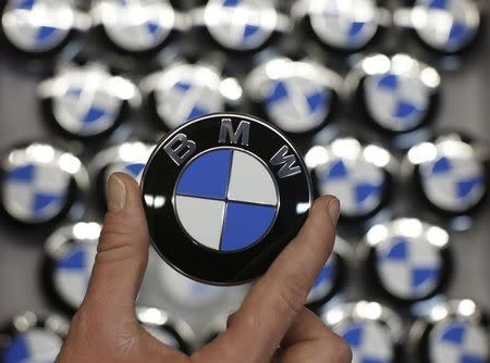 An employee holds a BMW logo on the production line of the BMW C evolution electric maxi-scooter at the BMW Berlin motorcycle plant February 23, 2015. REUTERS/Fabrizio Bensch