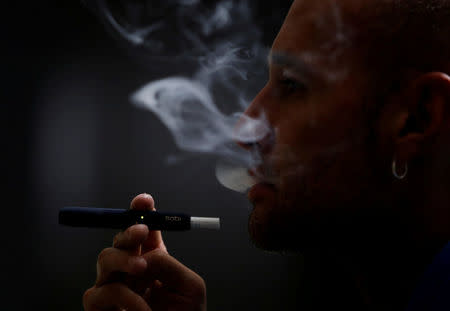 FILE PHOTO: A man poses for a photograph while using a Philip Morris iQOS smoking device, in Bogota, Colombia November 14, 2017. REUTERS/Jaime Saldarriaga/File Photo