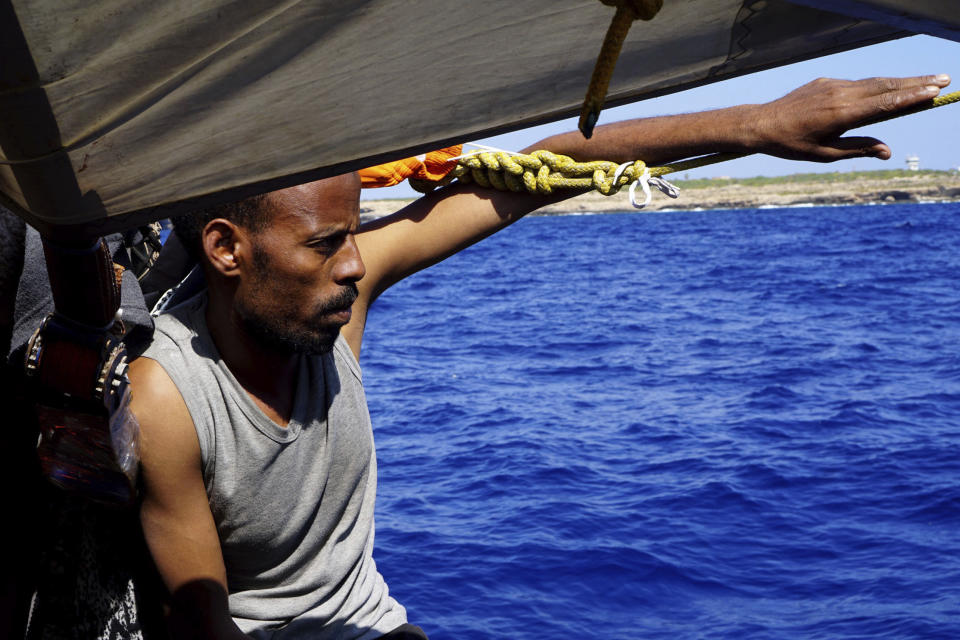 A migrant sits on the deck of the Open Arms vessel in front of island of Lampedusa, southern Italy, Tuesday, Aug. 20, 2019. The Spanish humanitarian rescue ship Open Arms says another man had to be rescued after jumping in the sea as the stand-off with Italy, which won't permit it access to a port, entered its 19th day. Open Arms described the situation on board Tuesday as ''desperate,'' saying that a man threw himself in the water trying to reach trying to reach land in plain view, while at the same moment a woman suffered a panic attack. (AP Photo/Francisco Gentico)