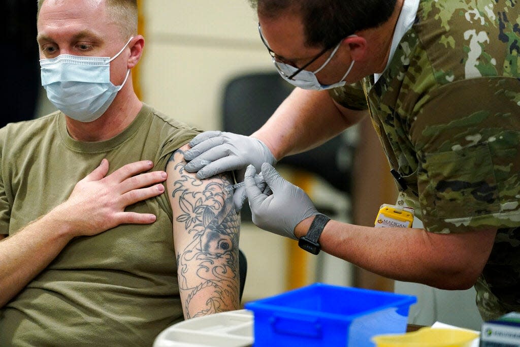 FILE - Staff Sgt. Travis Snyder, left, receives the first dose of the Pfizer COVID-19 vaccine given at Madigan Army Medical Center at Joint Base Lewis-McChord in Washington state, Dec. 16, 2020, south of Seattle.