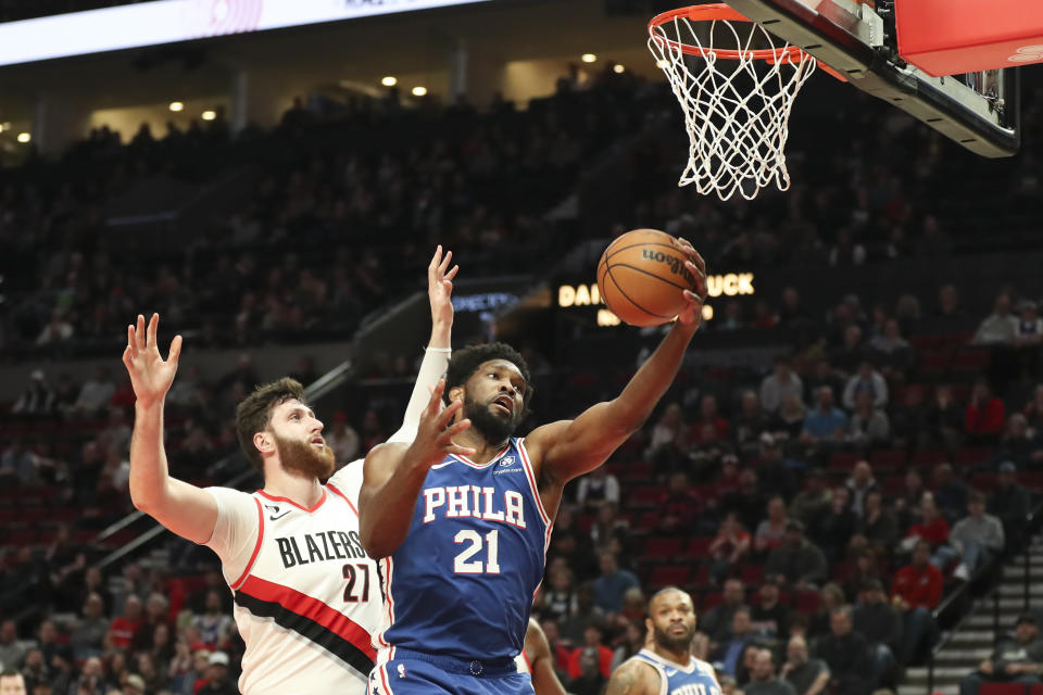 Philadelphia 76ers center Joel Embiid (21) drives to the basket as Portland Trail Blazers center Jusuf Nurkic (27) defends during the first half of an NBA basketball game in Portland, Ore., Thursday, Jan. 19, 2023. (AP Photo/Amanda Loman)