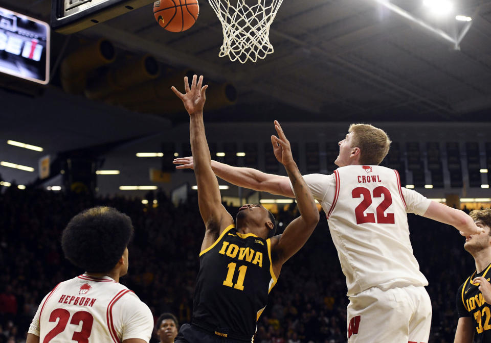 Iowa guard Tony Perkins (11) makes the game winning basket under pressure from Wisconsin guard Chucky Hepburn (23) and forward Steven Crowl (22) during overtime in an NCAA college basketball game, Saturday, Feb. 17, 2024, in Iowa City, Iowa. (AP Photo/Cliff Jette)