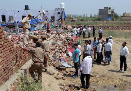 Onlookers and police stand amid the debris of the wall that collapsed on a crowd of people celebrating a wedding on Wednesday night, in Bharatpur, in Rajasthan, India, May 11, 2017. REUTERS/K.K.Arora