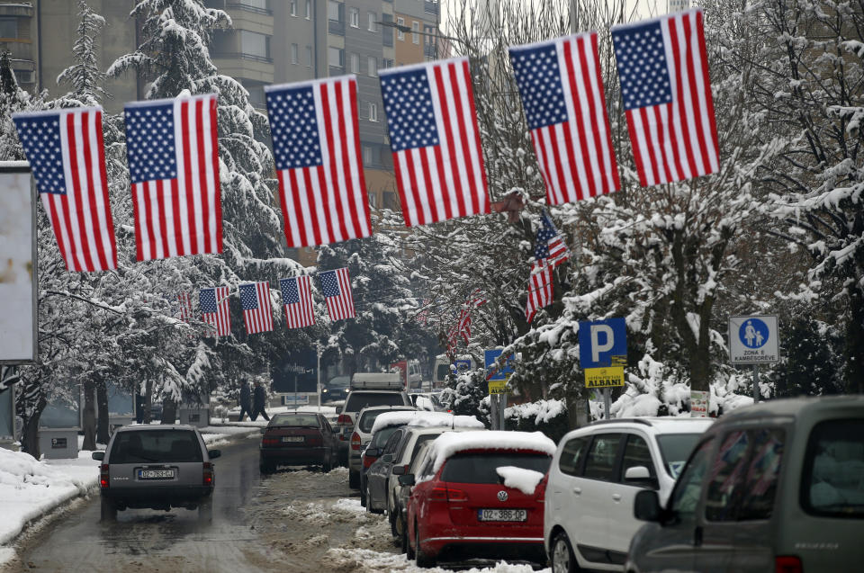 A car drives through a street decorated with American flags in the southern, ethnic Albanian-dominated part of ethnically divided town of Mitrovica, Kosovo, Friday, Dec. 14, 2018. Kosovo's parliament overwhelmingly approved the formation of an army, a move that has angered Serbia which says it would threaten peace in the war-scarred region. (AP Photo/Darko Vojinovic)