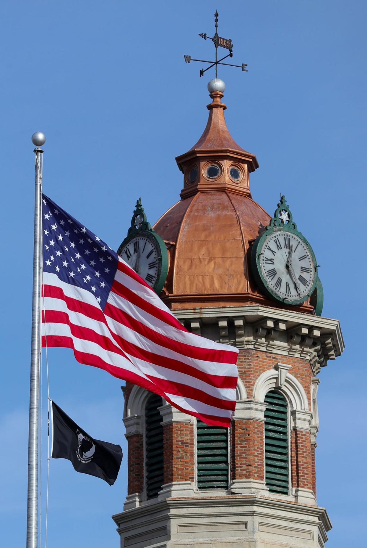 The American flag blows in the wind in front of the Geauga County Courthouse clocktower.