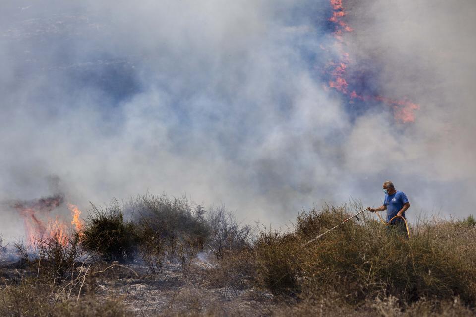 An Israeli worker from the Nature and Parks Authority attempts to extinguish a fire caused by a incendiary balloon launched by Palestinians from the Gaza Strip, on the Israeli side of the border between Israel and Gaza, near Or HaNer Kibbutz, Wednesday, Aug. 12, 2020. The Israeli military said it attacked a number of Hamas targets in the Gaza Strip early Wednesday in response to days of launches of explosives-laden balloons from Gaza into Israeli territory. Israel says it holds Gaza's Hamas rulers responsible for all fire emanating from the territory. (AP Photo/Tsafrir Abayov)