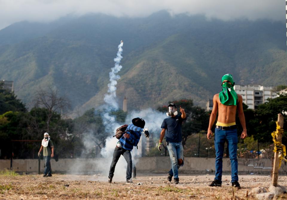 A demonstrator throws back a teargas canister towards police lines, during clashes in an anti-government protest in Caracas, Venezuela, Monday, March 10, 2014. The Venezuelan government and opposition appear to have reached a stalemate, in which street protests continue almost daily while the opposition sits out a peace process it calls farcical. (AP Photo/Alejandro Cegarra)