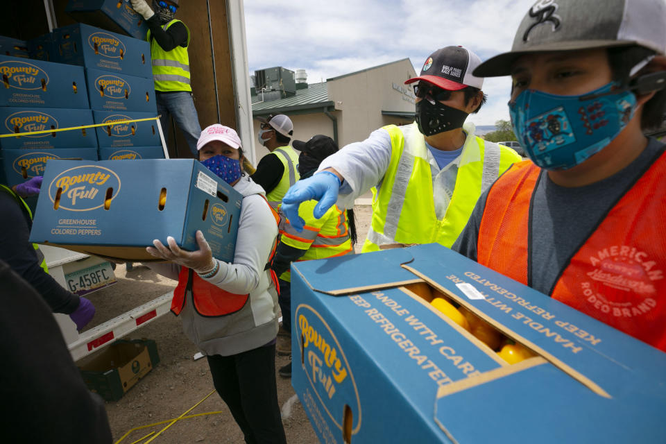 Navajo Nation President Jonathan Nez, center, and Isaiah Tsosie, right, an office specialist with the Coyote Canyon chapter, move food for distribution in Coyote Canyon, N.M., on the Navajo Nation on May 15, 2020. | David Wallace—The Republic/USA Today Network/Sipa USA