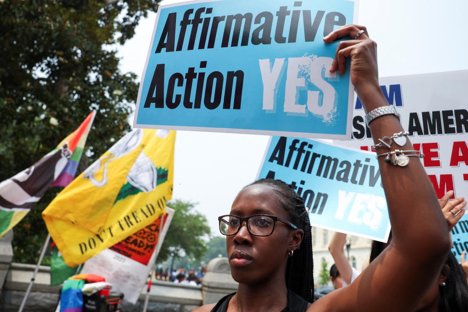 A woman holds a sign saying: Affirmative Action Yes.