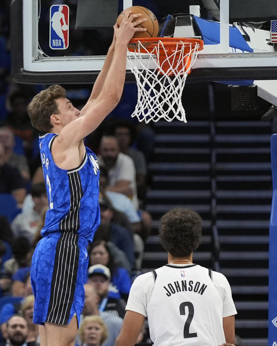 Orlando Magic forward Franz Wagner, left, dunks as Brooklyn Nets forward Cameron Johnson (2) watches during the first half of an NBA basketball game Wednesday, March 13, 2024, in Orlando, Fla. (AP Photo/John Raoux)