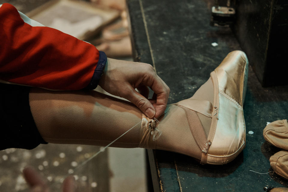 Unity Phelan sews her pointe shoe ribbons in place. 