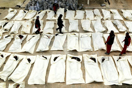 Workers document and count dead bodies, which according to the rebel fighters, were members of forces loyal to Syria's President Bashar al-Assad, before burying them in Aleppo, Syria February 23, 2015. REUTERS/Mahmoud Hebbo/File Photo
