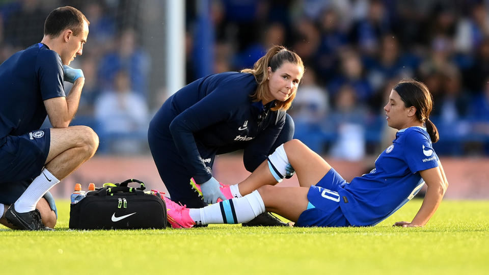 Sam Kerr is attended to by a Chelsea trainer.