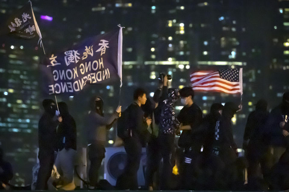Protestors wave flags at a rally in Hong Kong, Thursday, Dec. 12, 2019. Protesters in Hong Kong have written hundreds of Christmas cards for detainees jailed in the city's pro-democracy movement. At a rally on Thursday night, protesters promised on the cards that detainees won't be forgotten as they face spending the festive season behind bars. (AP Photo/Mark Schiefelbein)
