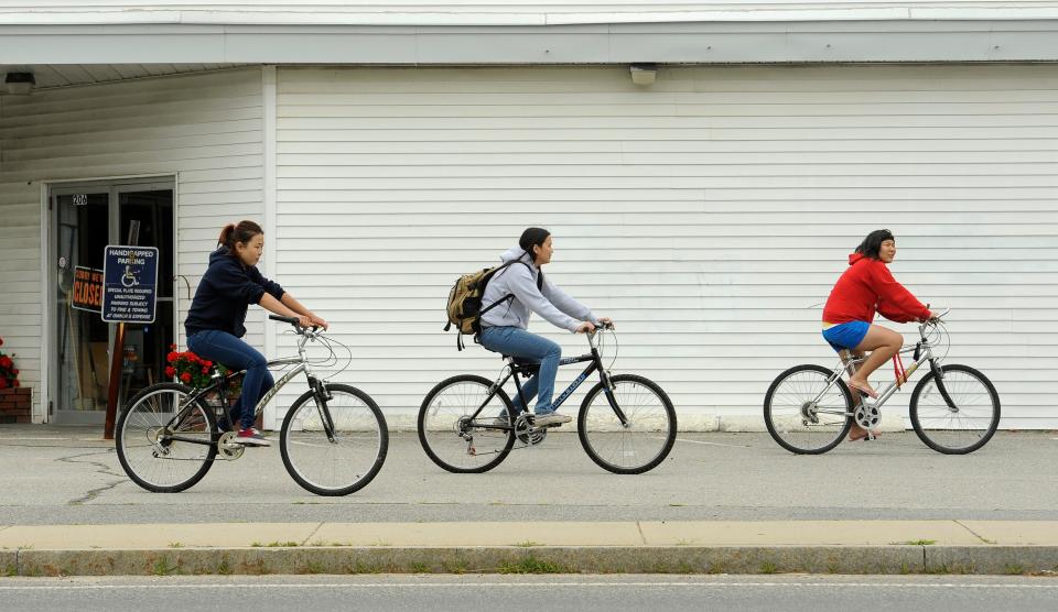 Schonchalay Khovalyg and Saryuna Gatapova, both of Russia, and Anastasia Chuluunbaatar of Mongolia, left to right, ride their bikes along Barnstable Road in Hyannis looking for a second job in addition to working at Dunkin Donuts, in 2012.