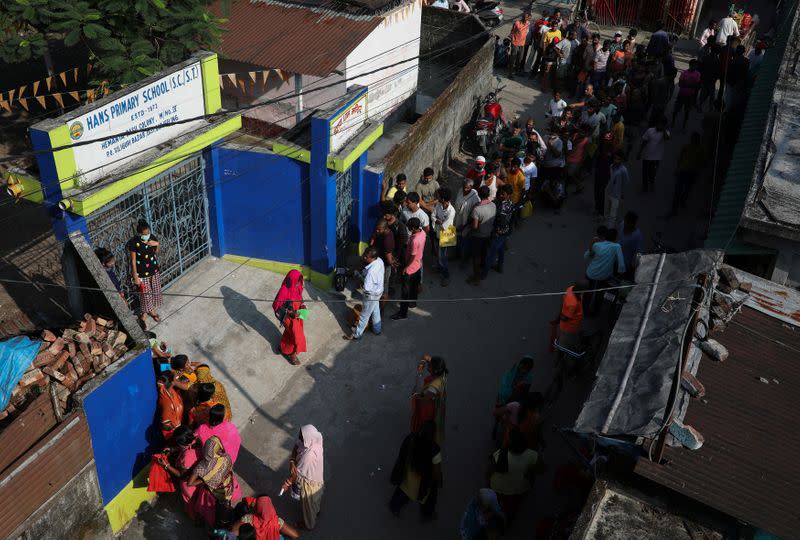 People stand in a queue to receive a dose of COVISHIELD vaccine, outside a vaccination centre in Siliguri