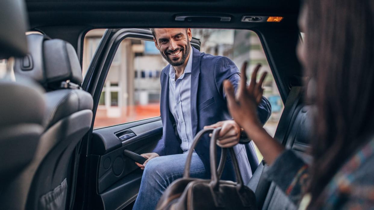 Man and woman, multi-ethnic couple ridding on back seat of a car, ride sharing in city.