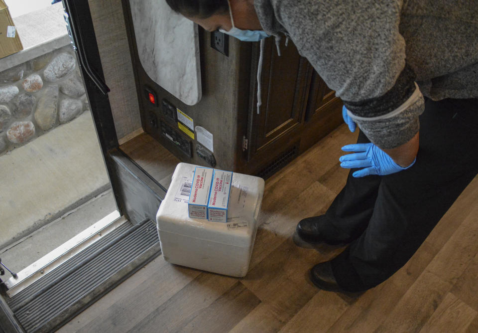 In this Thursday, April 29, 2021, photo, a Blackfeet tribe nurse examines a delivery of Moderna and Pfizer COVID-19 vaccines that will be given to Canadian residents at the Piegan-Carway border crossing near Babb, Mont. The Blackfeet tribe gave out surplus vaccines to its First Nations relatives and others from across the border. (AP Photo/Iris Samuels)