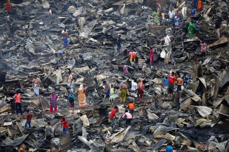Slum dwellers are seen searching for their belongings from ashes after fire broke out on their shelters in Dhaka