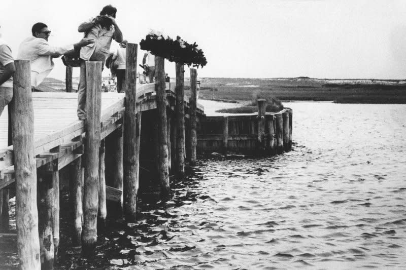 Mourners throw flowers off the Dike Bridge on July 19, 1979, the 10th anniversary of the day Sen. Edward Kennedy's car plunged off the bridge, killing Mary Jo Kopechne. UPI File Photo