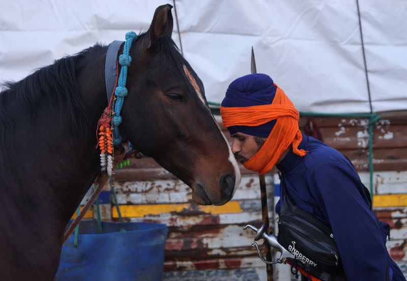 A nihang or Sikh warrior kisses a horse at a protest site where farmers are marching towards New Delhi to press for the better crop prices promised to them in 2021, at Shambhu Barrier