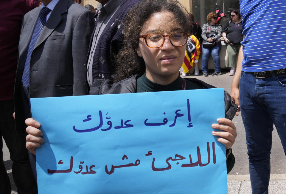 A protester holds a sign reading "Know your enemy - the refugee is not your enemy" in Arabic at a workers' day march held by leftist groups in Beirut, Lebanon, Monday, May 1, 2023. The slogan came in response to increased pressure by Lebanese authorities on Syrian refugees in recent weeks, including raids, arrests and deportations. (AP Photo/Hussein Malla)