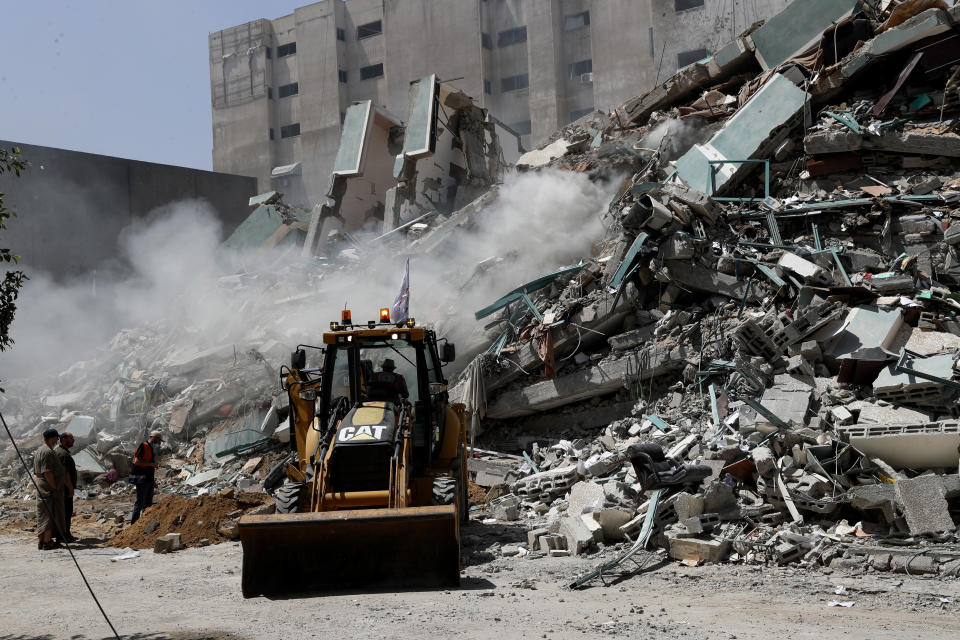 Workers clear the rubble of a building that was destroyed by an Israeli airstrike on Saturday that housed The Associated Press, broadcaster Al-Jazeera and other media outlets, in Gaza City, Sunday, May 16, 2021. (AP Photo/Adel Hana)