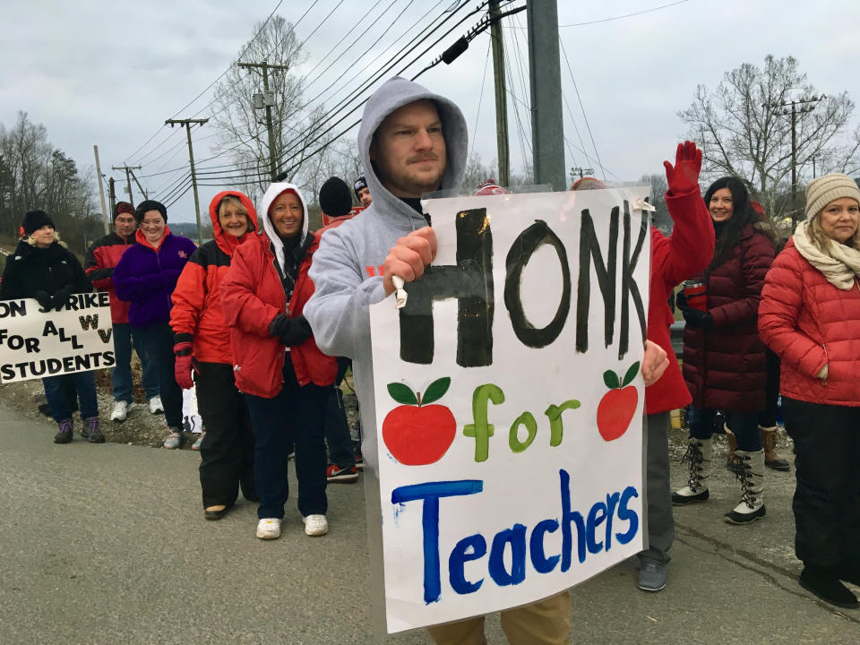 Striking teachers wave at passing cars outside Poca High School Tuesday, Feb. 19, 2019, in Poca, W.Va. Poca is in Putnam County, the only county in the state where public schools were held on the first day of the strike. (AP Photo/John Raby)