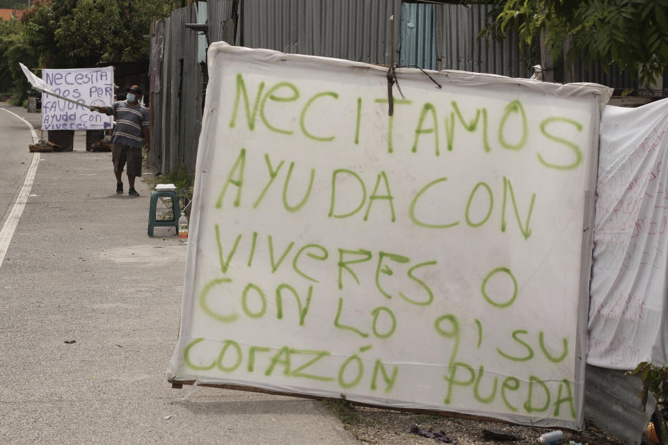 Letreros se despliegan para pedir comida a los autos que pasan por la Carretera de Oro en Ilopango, El Salvador, el martes 19 de mayo de 2020. (AP Foto/Salvador Melendez)